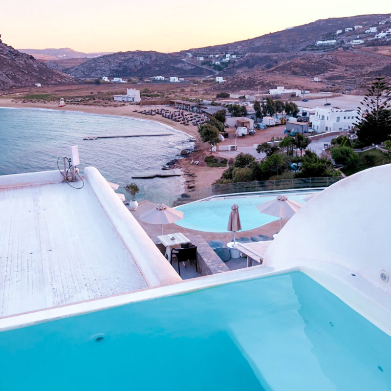 Overlooking the communal infinity pool with sea views in Panormos Village hotel (Mykonos - Greece)