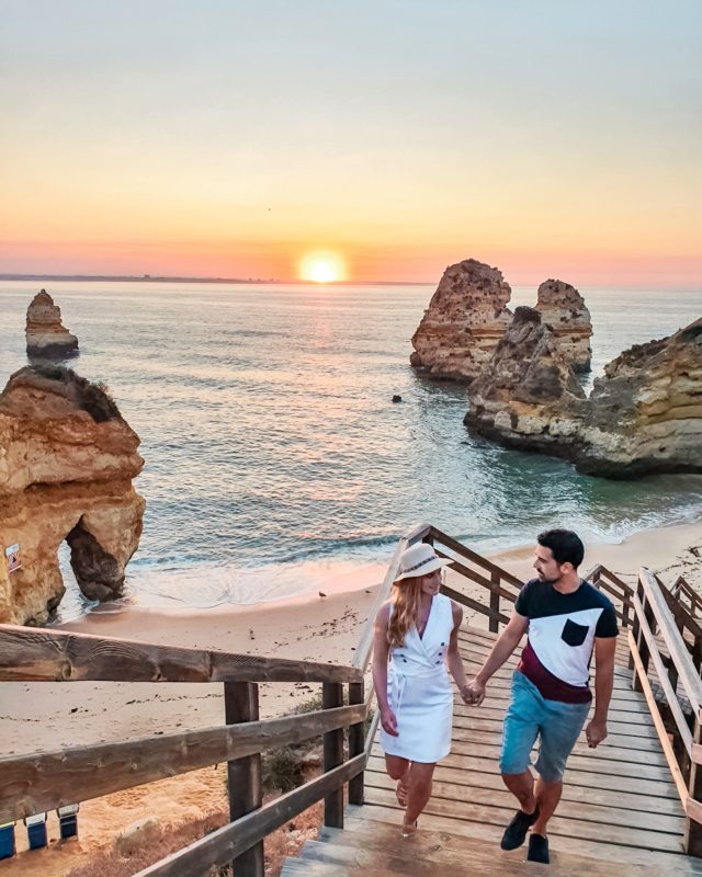 Couple posing at Praia do Camilo in Algarve, Portugal during sunrise