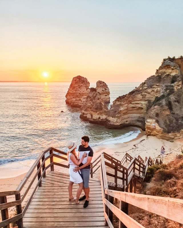 Couple posing at Praia do Camilo in Algarve, Portugal during sunrise