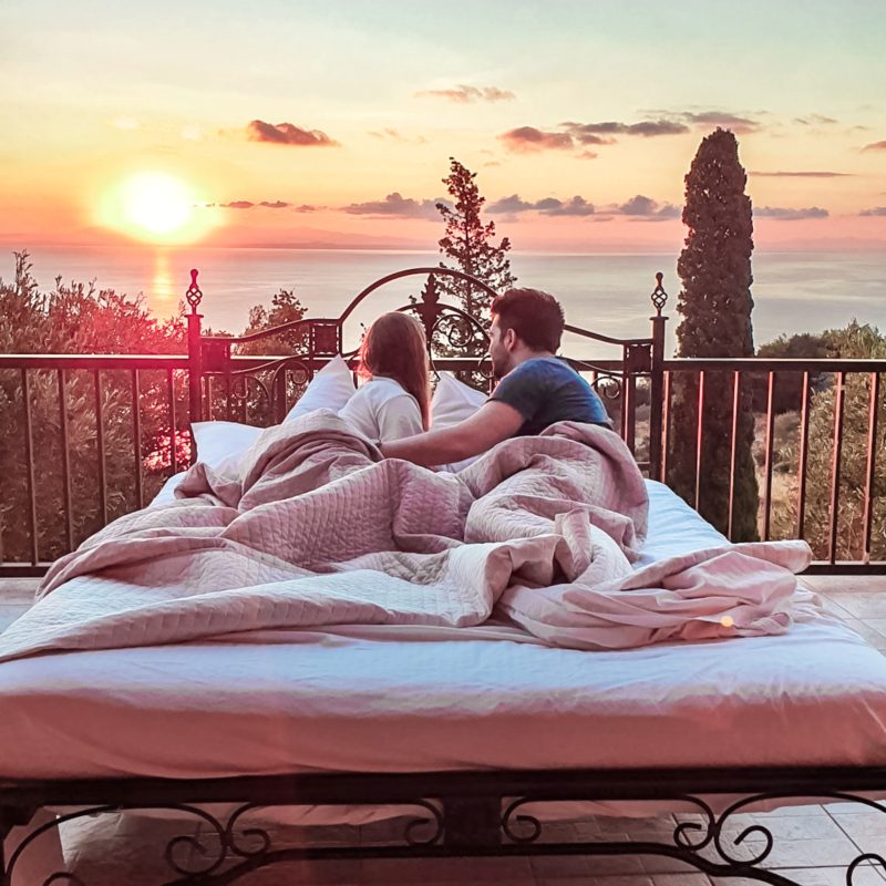 Couple watching sunrise in bed at Armyra Villas in Zakynthos, Greece