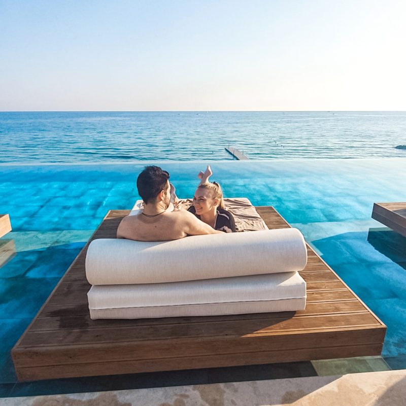 Couple relaxing on the sun loungers at the communal infinity pool at Lesante Blu (Zakynthos, Greece)