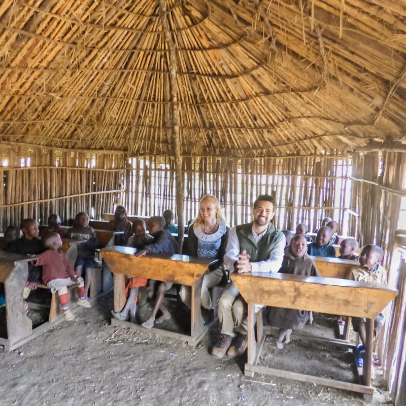 Travel Couple visiting a primary school at a Maasai Village in Tanzania, Africa