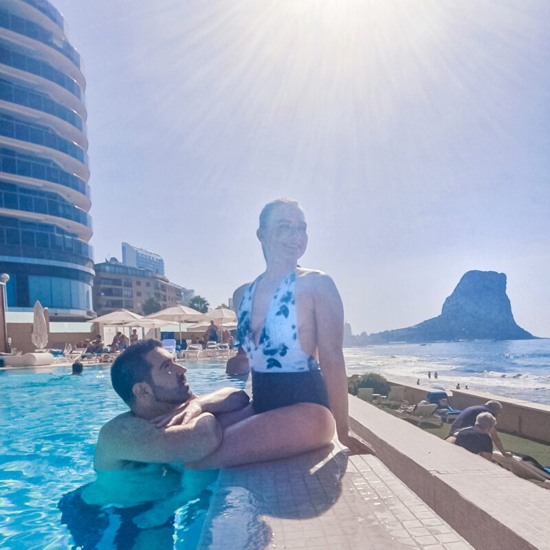Couple posing in infinity pool with Ifach rock views at hotel Sol Y Mar in Calpe, Costa Blanca, Spain.
