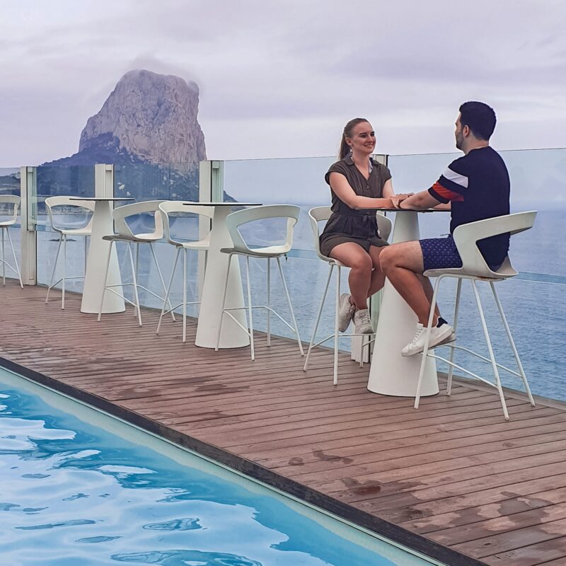 Couple posing at poolside bar with Ifach rock views at Bahia hotel in Calpe, Costa Blanca, Spain