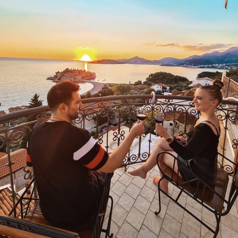 Couple watching sunset with Sveti Stefan views on private balcony at Villa Edelweiss in Montenegro