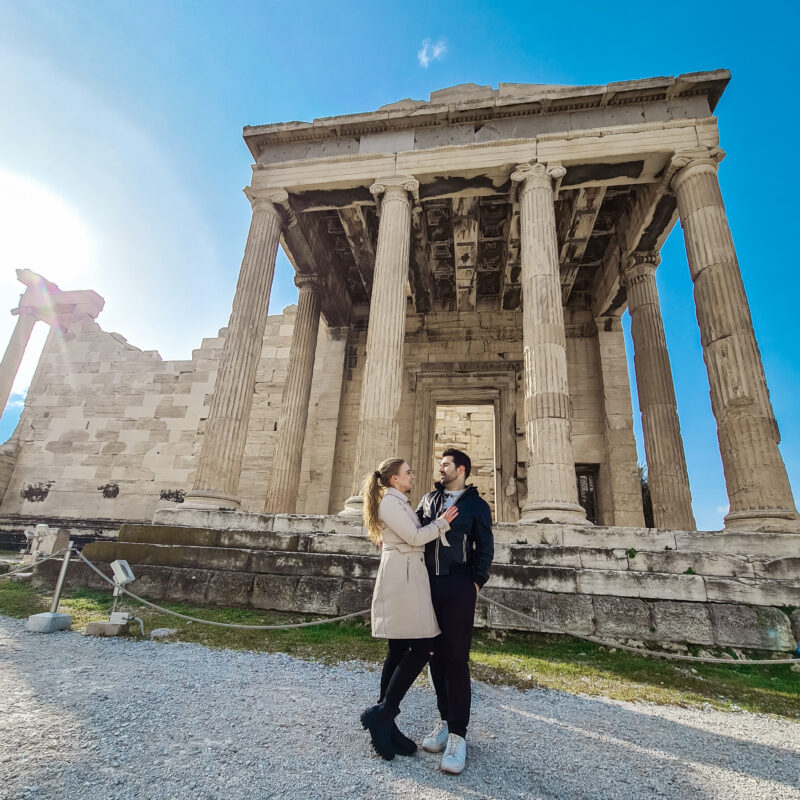 Travel couple posing in front of Erechteion at Acropolis of Athens in Greece