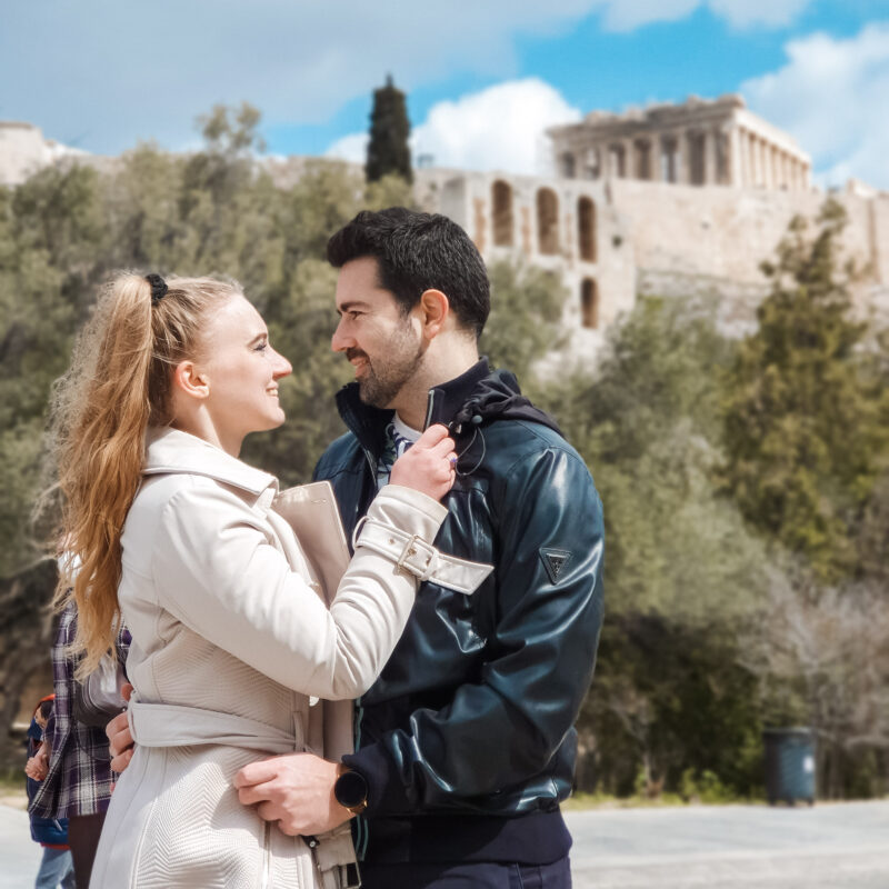 Travel Couple posing in park with Acropolis of Athens in background