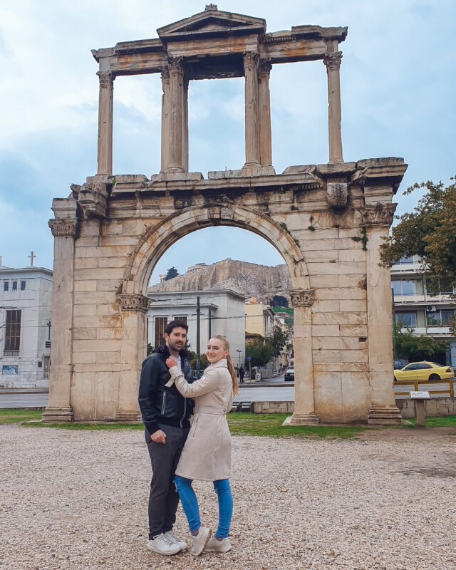 Travel couple posing in front of Hadrian's Arch in Athens, Greece