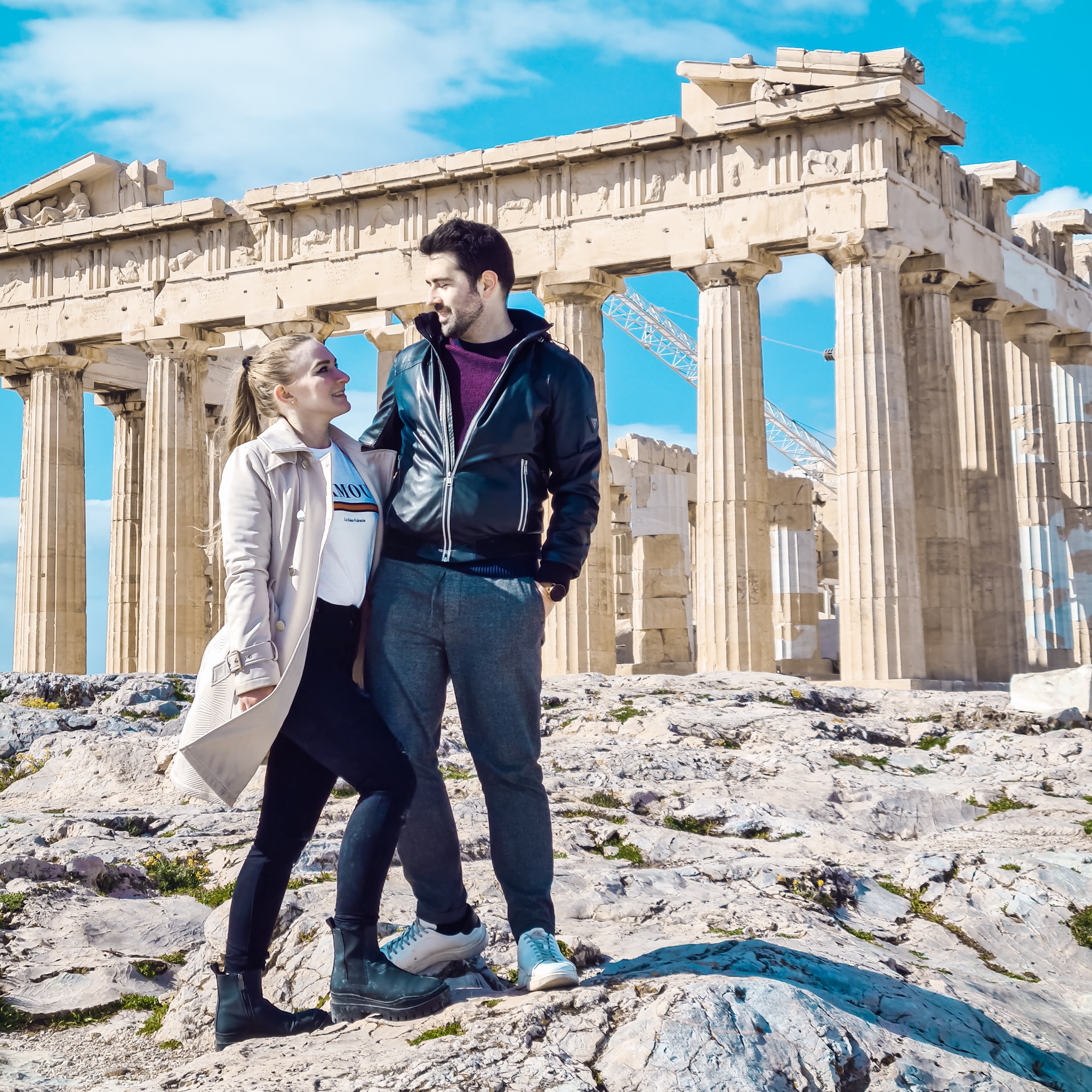 Travel couple posing in front of Parthenon at Acropolis of Athens in Greece