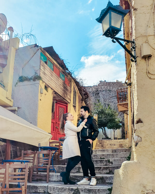 Travel Couple posing in the streets of Anafiotika at the Plaka district in Athens, Greece