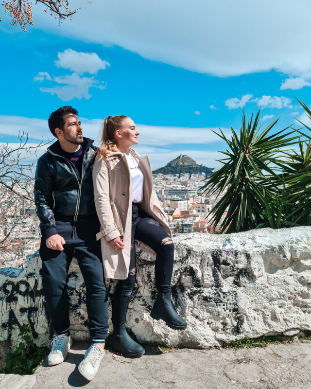 Travel couple posing at the viewpoint of Lycabettus Hill in the Plaka district of Athens, Greece