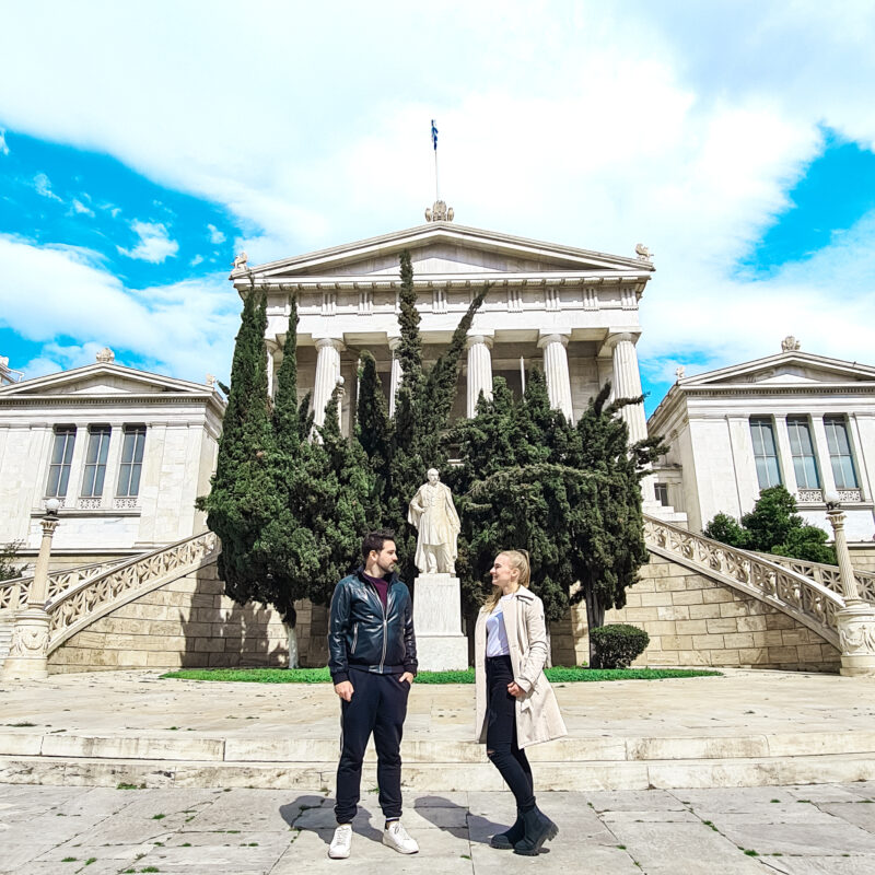 Travel couple posing in front of National Library of Greece in Athens