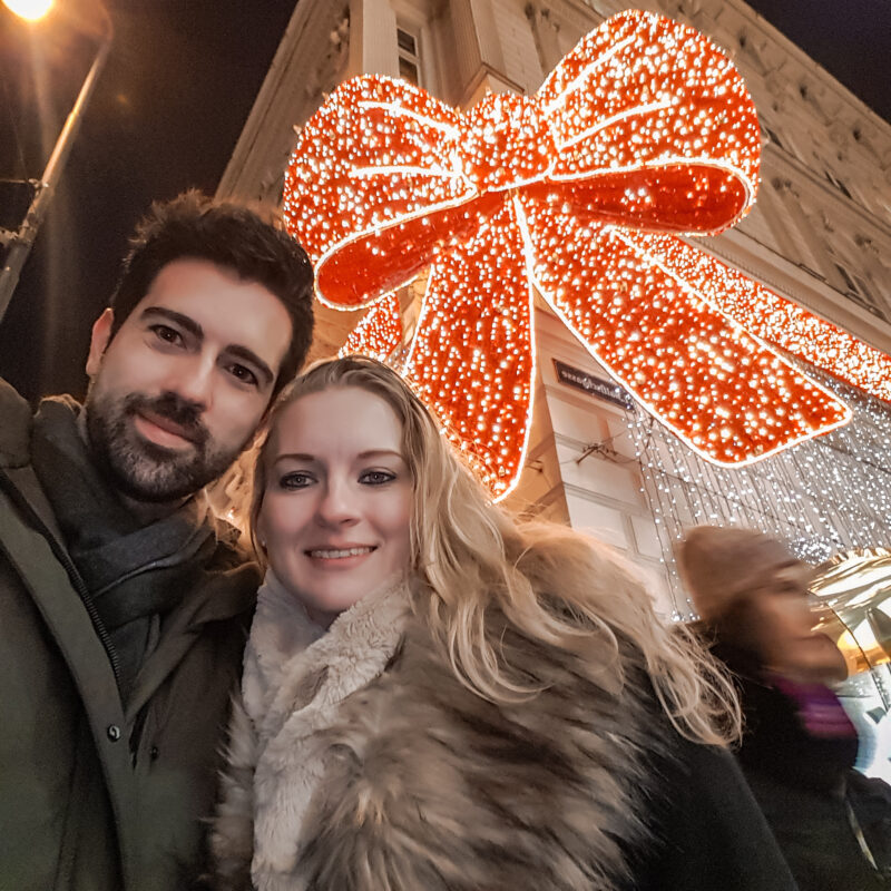 Couple posing with Christmas lights at Swarovski store in Vienna, Austria