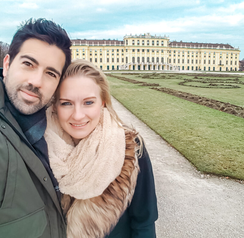 Couple posing in front of Schonbrunn Palace in Vienna, Austria