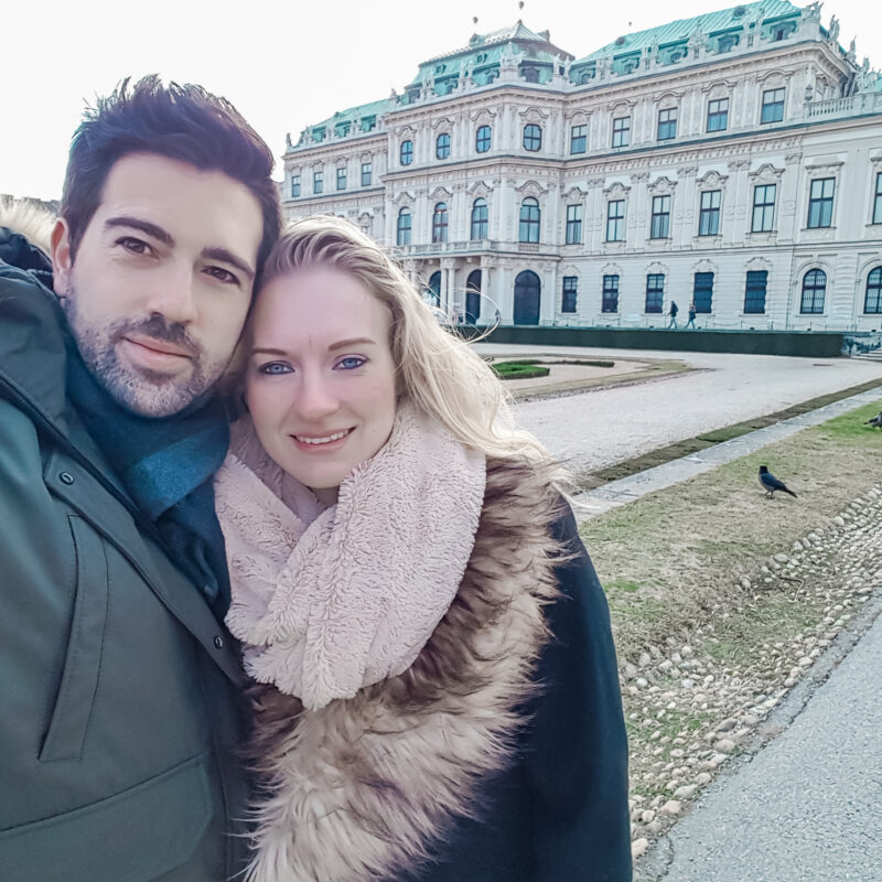 Couple posing in front of Belvedere Palace in Vienna, Austria