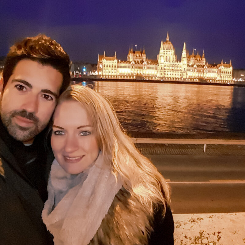 Selfie of a travel couple in front of the Hungarian Parliament Building in Budapest, Hungary at night