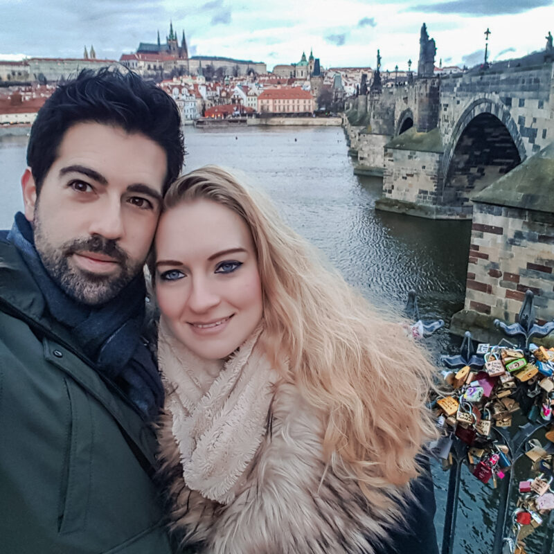 Couple posing in front of the Charles Bridge in Prague, Czech Republic