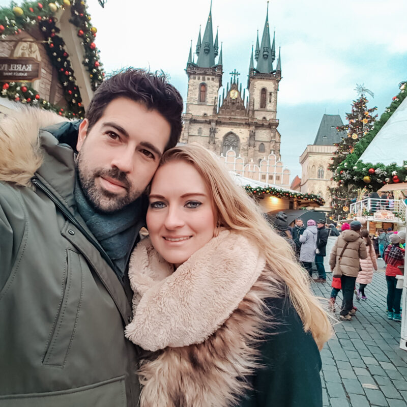 Couple posing at Christmas market at Old Town Square in Prague, Czech Republic