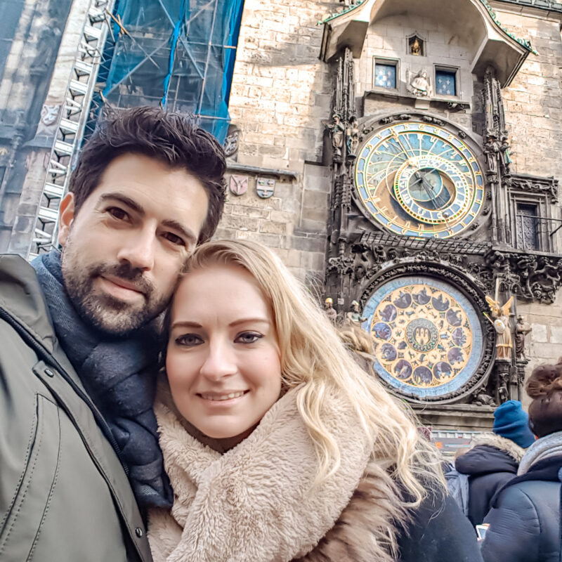 Couple posing in front of the Astronomical Clock in Prague, Czech Republic