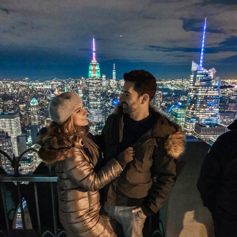 Travel Couple admiring the New York City skyline at Top of the Rock at night