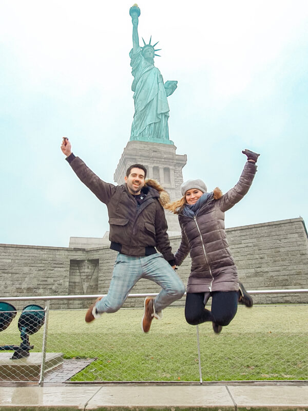 Travel Couple at the Statue of Liberty in New York City