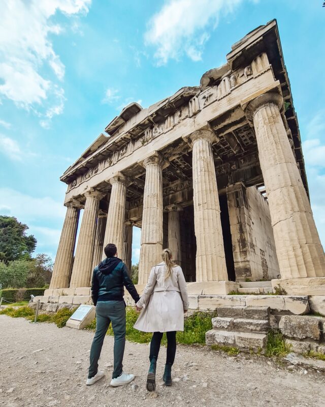 Travel Couple posing in front of the Temple of Hephaestus at the Ancient Agora of Athens, Greece