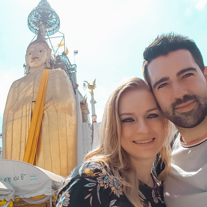 Travel Couple taking a selfie in front of the Standing Buddha in Bangkok, Thailand