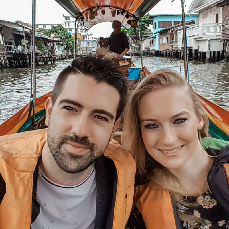 Travel Couple taking a traditional long-tail boat trip in Bangkok, Thailand