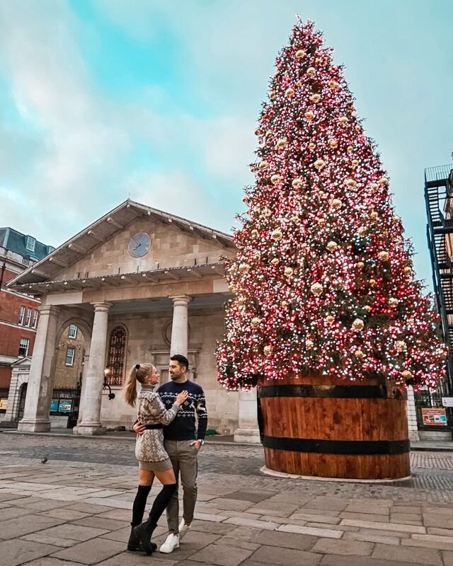 Travel couple posing with the Christmas Tree at the Piazza in Covent Garden, London