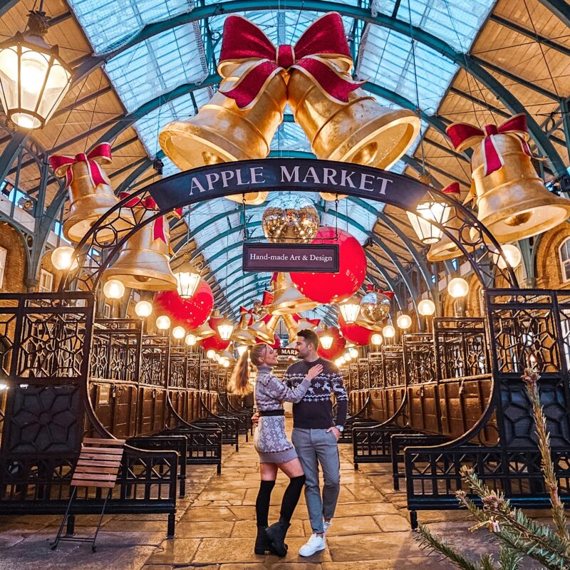 Travel Couple posing with Christmas Decorations at the Apple Market in Covent Garden London