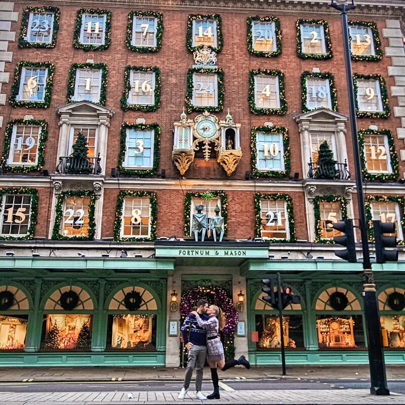 Travel Couple posing with Christmas Decoration advent calendar at Fortnum & Mason London