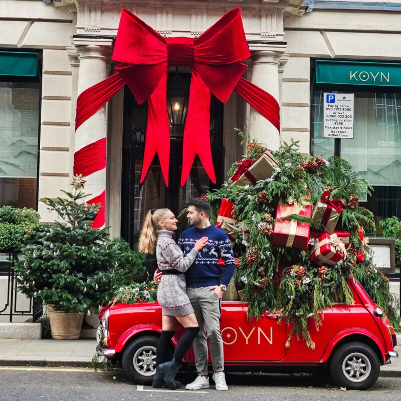 Travel Couple posing with Christmas Decorations at Koyn in Mayfair London