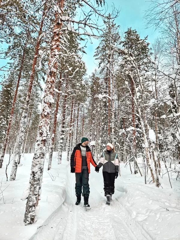 What to wear in Finnish Lapland in winter - Couple dressed for the Arctic Cold with ski jackets, ski pants, tube scarf, ear warmers and snow boots